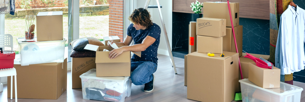 Helping My Son on the Autism Spectrum Transition to Adulthood Young man unpacking moving boxes in living room.