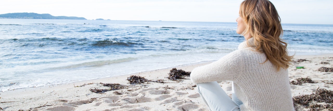 How I Answer Questions About the Future With My Medically Complex Son a woman sitting in the sand at the beach