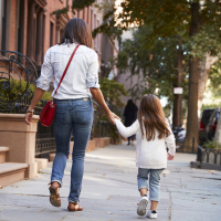 Mother and daughter walking down the street, back view