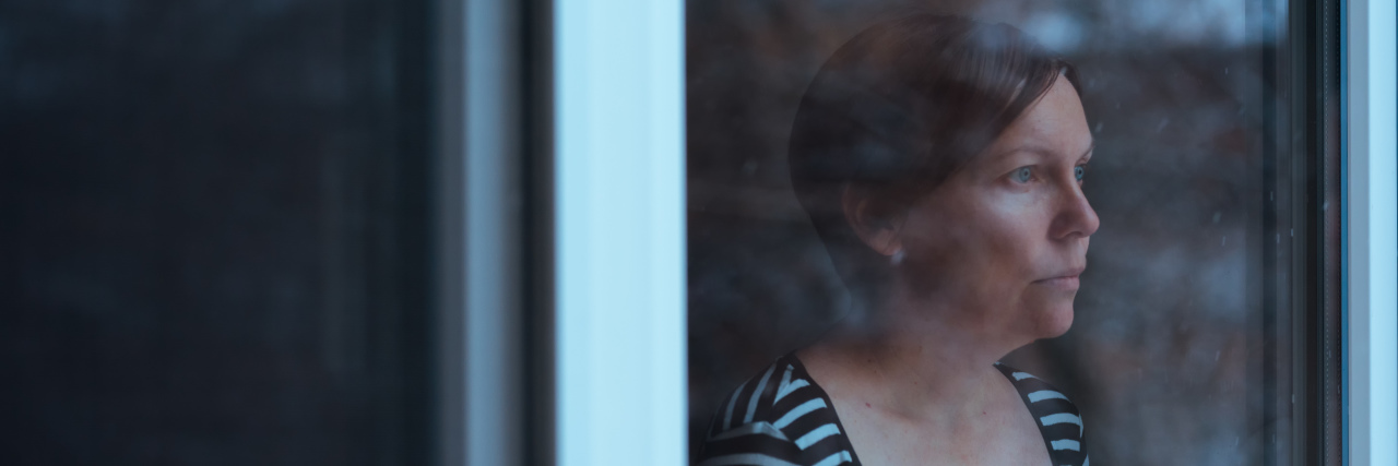 How I'm Accepting I May Never Get an Apology From Those Who Hurt Me woman with short red hair in a striped shirt looking out the window solemnly
