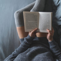 Woman reading book in bed.