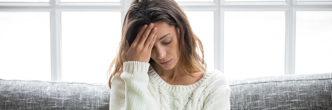 What It's Like Being Preyed Upon Online Because of My Chronic Illness Frustrated woman worried about problem sitting on sofa with laptop