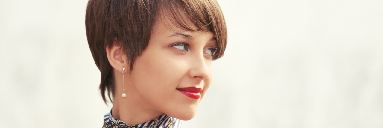 Why I Look Back Instead of Making New Resolutions With Chronic Illness woman with short brown hair and a handkerchief around her neck looking behind her with a soft smile