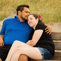 photo of author and husband sitting on a bench, husband kissing her forehead