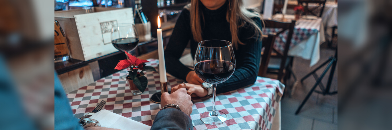 photo of couple in restaurant with hands meeting across table, a candle between them