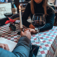 photo of couple in restaurant with hands meeting across table, a candle between them
