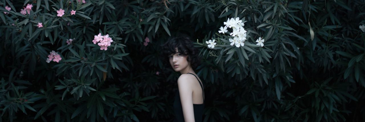 The Heaviness of Depression I Can't Escape With Bipolar Disorder woman under a trees and bushes looking behind her