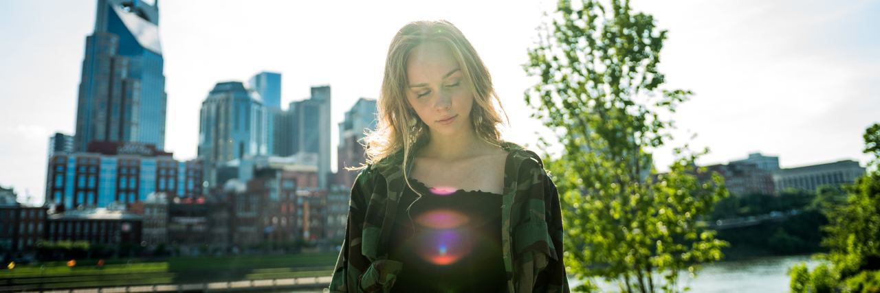 Addressing My Own Stigma Against Borderline Personality Disorder woman outside in front of a stream and a tree looking down