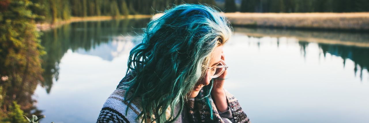 What I Want Others to Understand About Life With Chronic Illness woman sitting near a peaceful lake