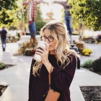 Woman drinking coffee in an outdoor courtyard.