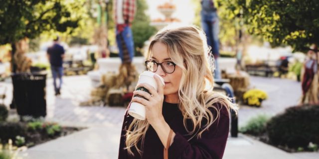 Woman drinking coffee in an outdoor courtyard.