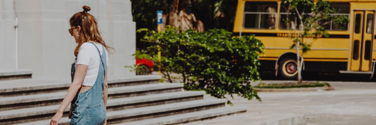 How School Bullying Caused My Anxiety photo of young woman crossing road at school with a yellow school bus in the background