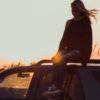 photo of woman sitting on car at sunset looking down in thoughtfulness