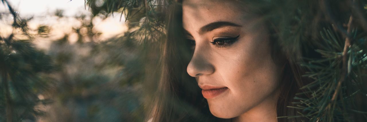 Toxic Relationships That Led to Depression Are Not Your Fault woman with wavy brown hair looking down, standing under a tree