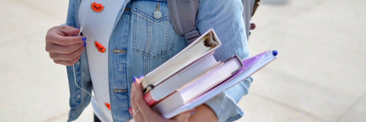 A woman with a backpack carrying books