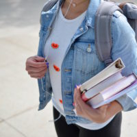 A woman with a backpack carrying books