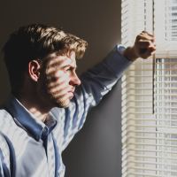 photo of man looking out of window with unhappy expression