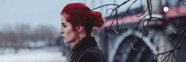 woman with red hair looking over a balcony with a snowy background