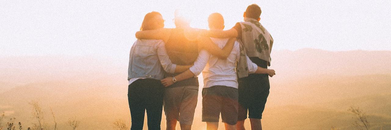 Combatting Loneliness and Finding Community With Schizophrenia Group of friends with arms around each other, standing together at sunset