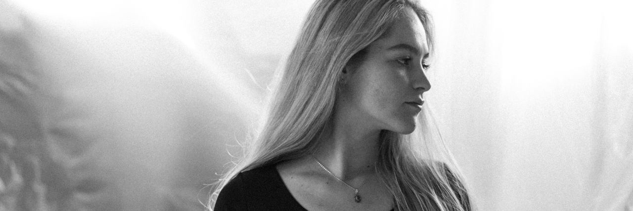 My Doctor's Comment About My Weight Triggered My Eating Disorder black and white photo of blonde woman in black sitting in front of white sheet or curtain, looking away