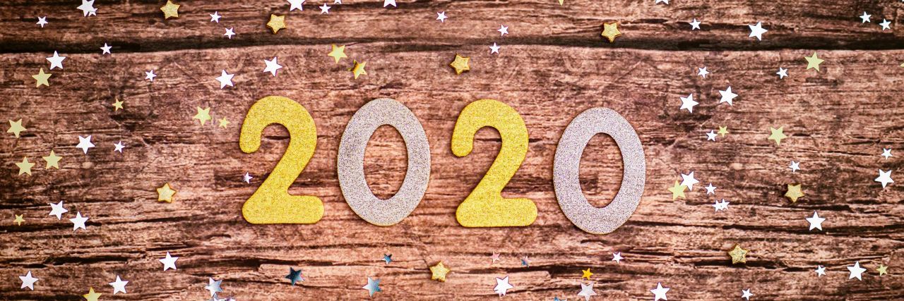 the numbers 2020 on a wooden table with confetti scattered around