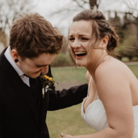 A man in a suit and a woman in a wedding dress laughing together outside