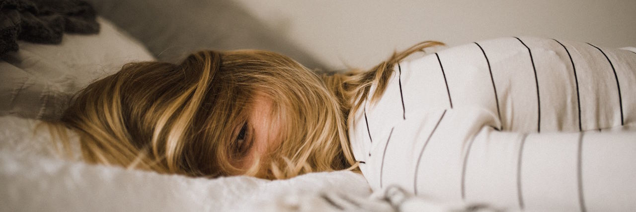 A Day in the Life in the Mind of a Mom With Anxiety and Depression Woman laying in bed , exhausted with eyes open