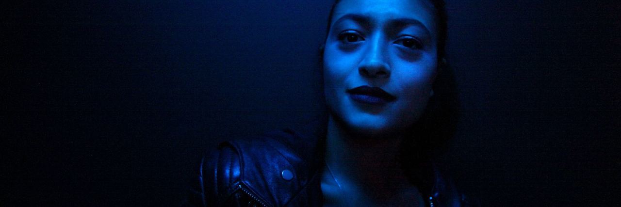 photo of woman in dark blue light posing for camera