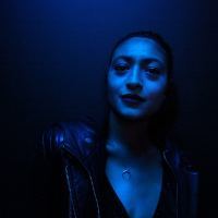 photo of woman in dark blue light posing for camera