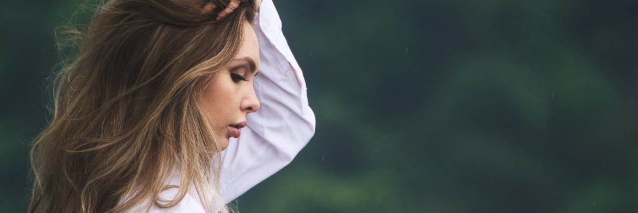 Families Need to Stop Supporting Sexual Abusers photo of woman with blonde hair raising hand to her hair, blurred trees in the background