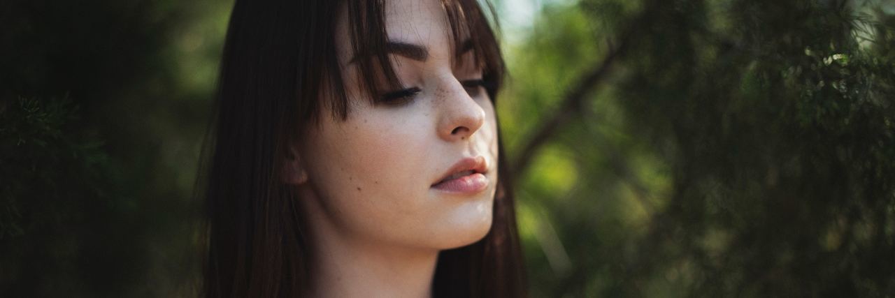 Using a 'Safe Word' to Cope With Anixety or Panic Attacks photo of dark haired woman standing in front of trees with eyes closed