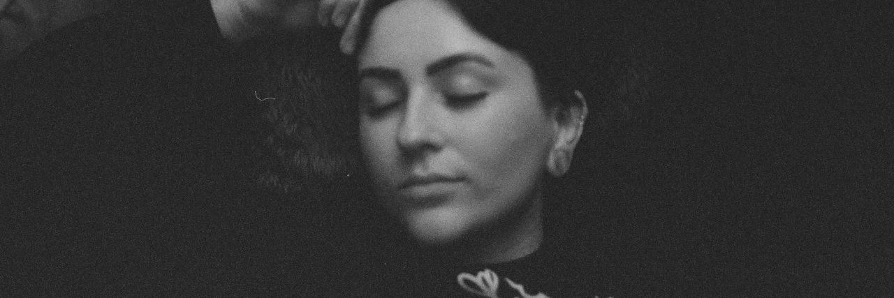 What Being Suicidal Feels Like When You Don't Want to Die black and white photo of woman lying down with eyes closed and arms raised above her head