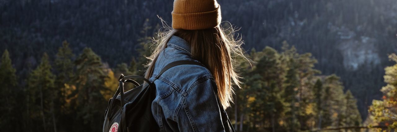 photo of woman in mountains or hiking with backpack hat and covering hair