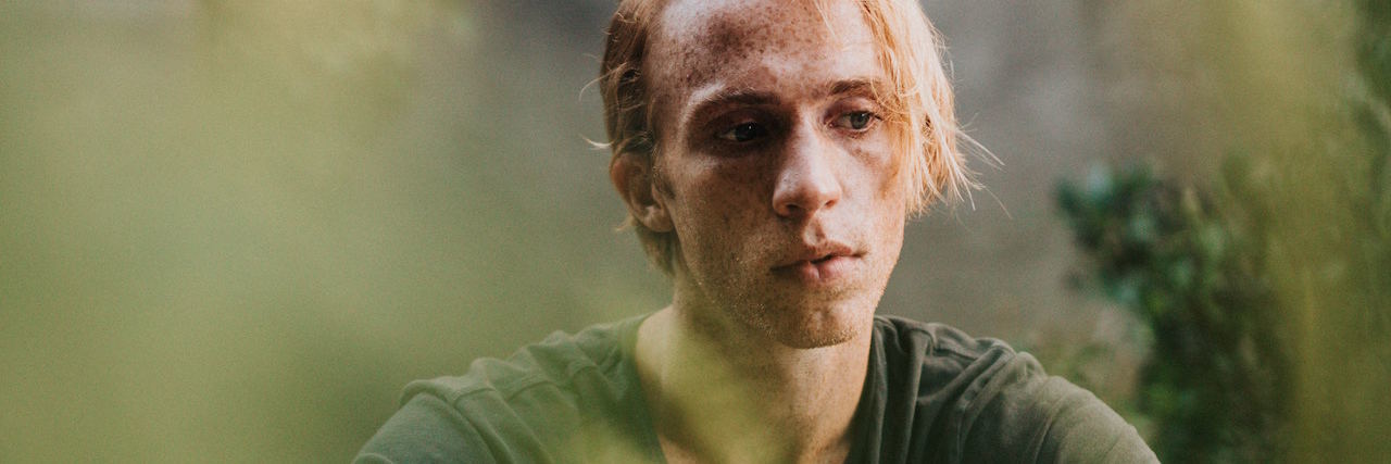 Having a Memory of Being Sexually Abused When You're Not 100% Sure A young man sitting in a field with grass around him