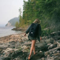 Woman wearing a backpack and walking on a rocky beach