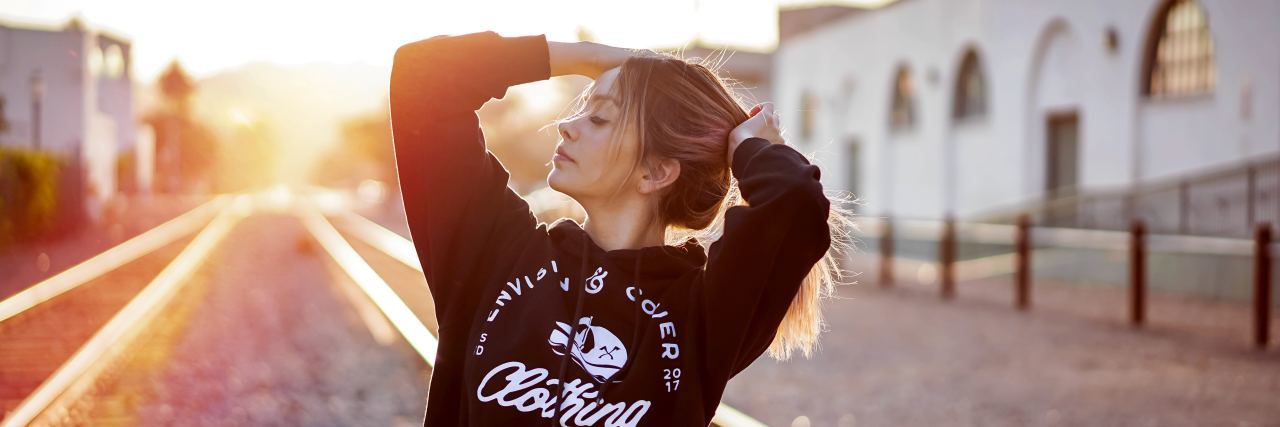 Reflecting on My Journey With Anxiety and How Therapy Saved Me young woman on a train track with a black sweatshirt, hands in her hair