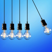 Group of hanging lightbulbs with one offset from the others.
