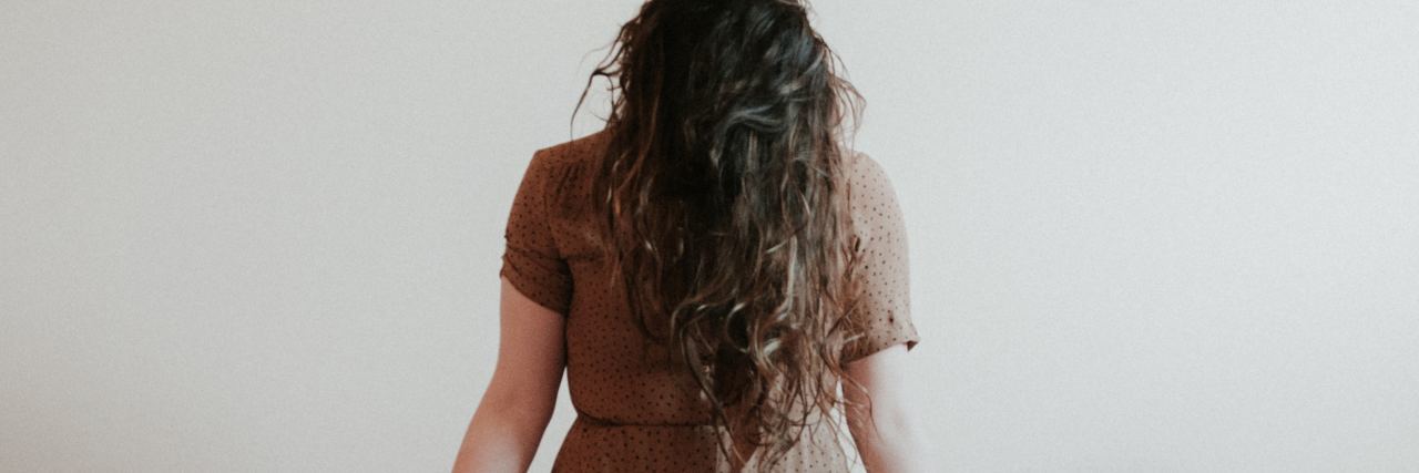 Feel Like People Aren't There for Me With My Mental Illness photo of woman kneeling against white background with hands open and facing camera, hair covering her face