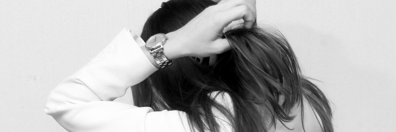 Read This If You Feel Pressured to Be 'Normal' in PTSD Recovery black and white photo of woman facing away from camera, covering head with her hands