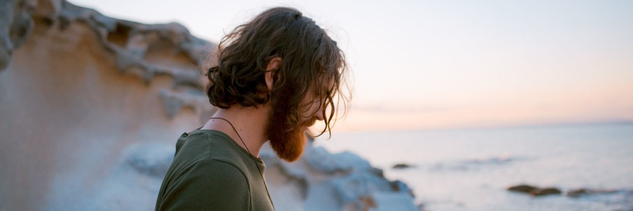 My OCD Does Not Define Me, I Am More Than My Disorder man on a beach with long hair looking down