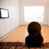 Woman sitting on sofa looking at a nearly empty room