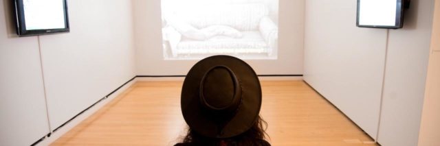 Woman sitting on sofa looking at a nearly empty room