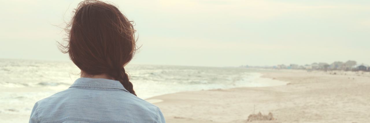 What Flares Feel Like With Chronic Pain and Achalasia close-up of the back of a woman facing the beach