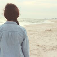close-up of the back of a woman facing the beach