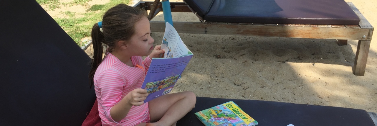 When Educators Underestimate My Child With Down Syndrome Elyse reading books.