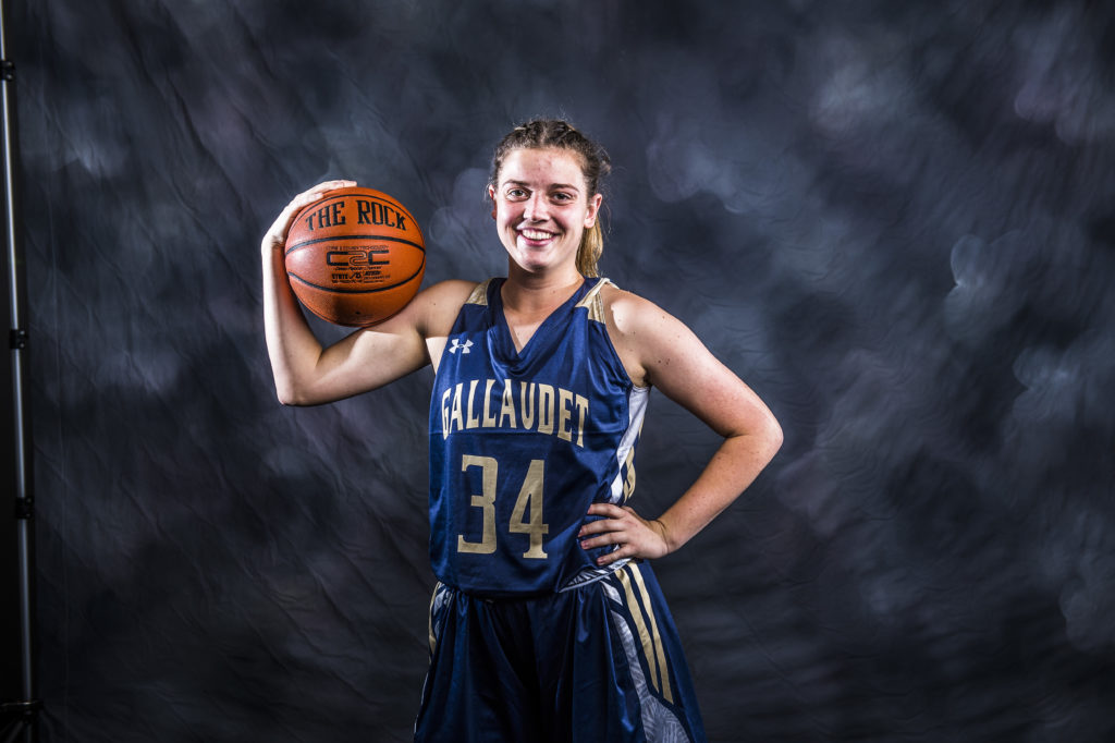 Hannah Neild in a blue basketball uniform holding a basketball on her shoulder