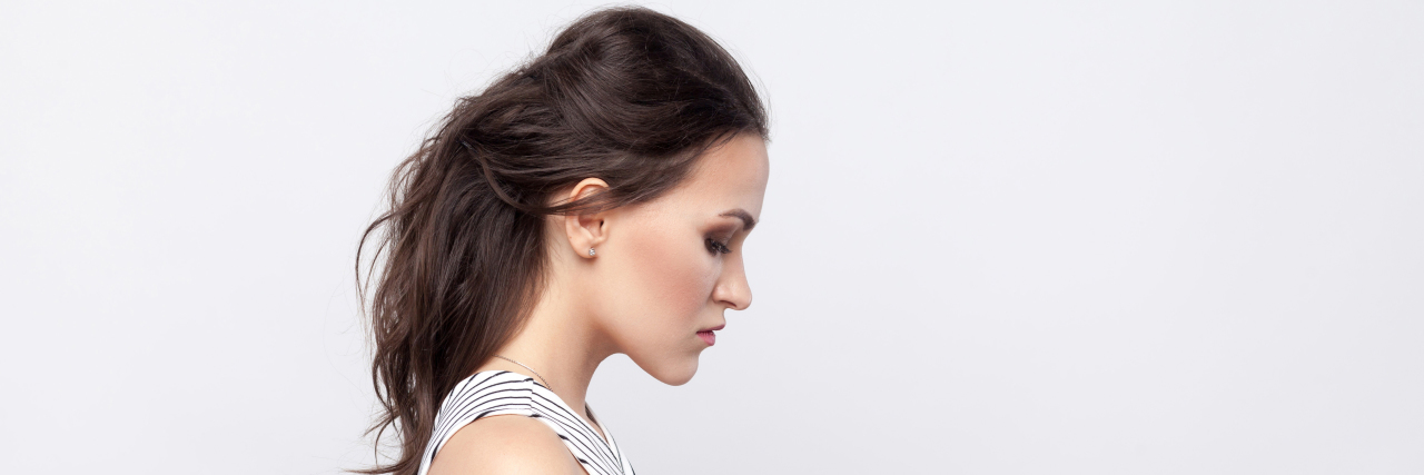 10 Tools and Resources to Help Trauma Survivors Find Help side view of a woman in a black and white striped dress with her brown her behind her, looking down