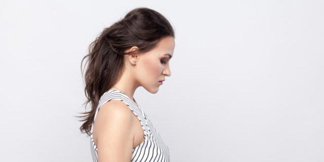 side view of a woman in a black and white striped dress with her brown her behind her, looking down