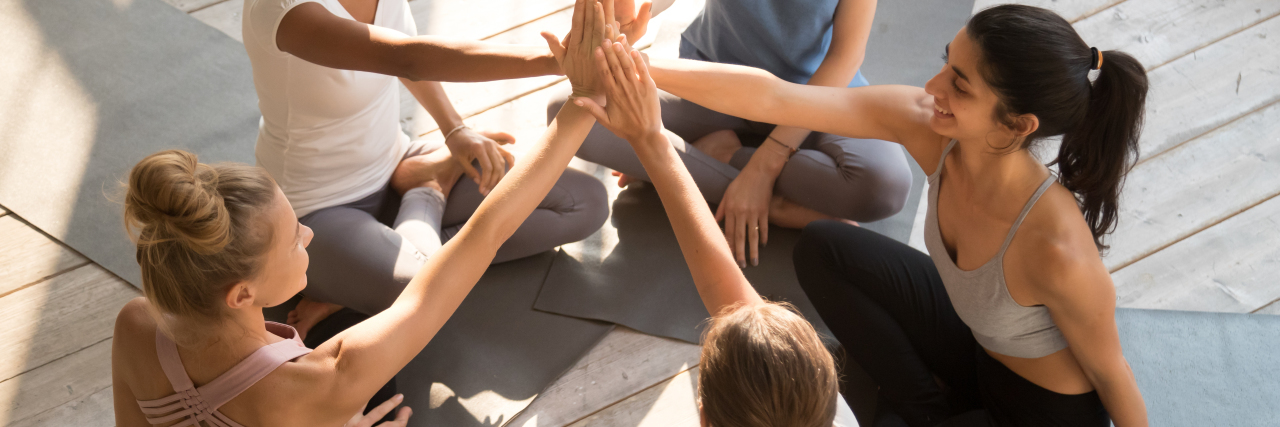 Looking Past Our Inner Circle for Support While Fighting an Illness A group of diverse women sitting in a circle and giving each other a supportive high five.