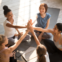 A group of diverse women sitting in a circle and giving each other a supportive high five.